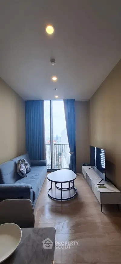 Modern living room with large window and city view, featuring stylish furniture and elegant decor.