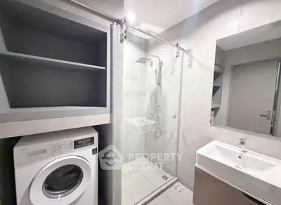 Modern bathroom with shower and washing machine in sleek apartment.
