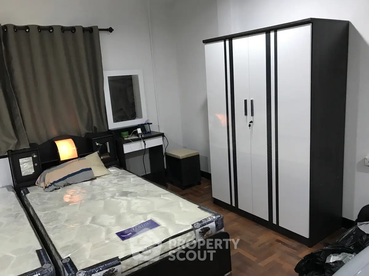 Cozy bedroom with twin beds, modern wardrobe, and stylish decor for a comfortable living experience.