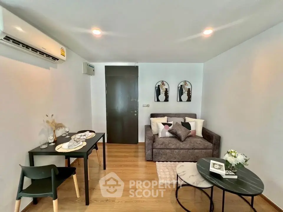 Cozy living room with modern decor and dining area, featuring stylish furniture and wooden flooring.