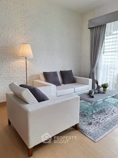 Elegant living room with white brick wall, modern furniture, and large window for natural light.