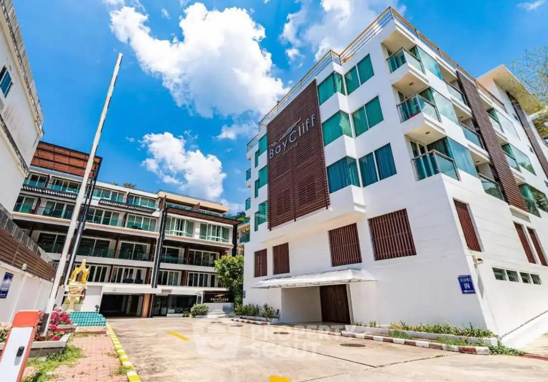 Modern apartment building with clear blue sky and spacious parking area.