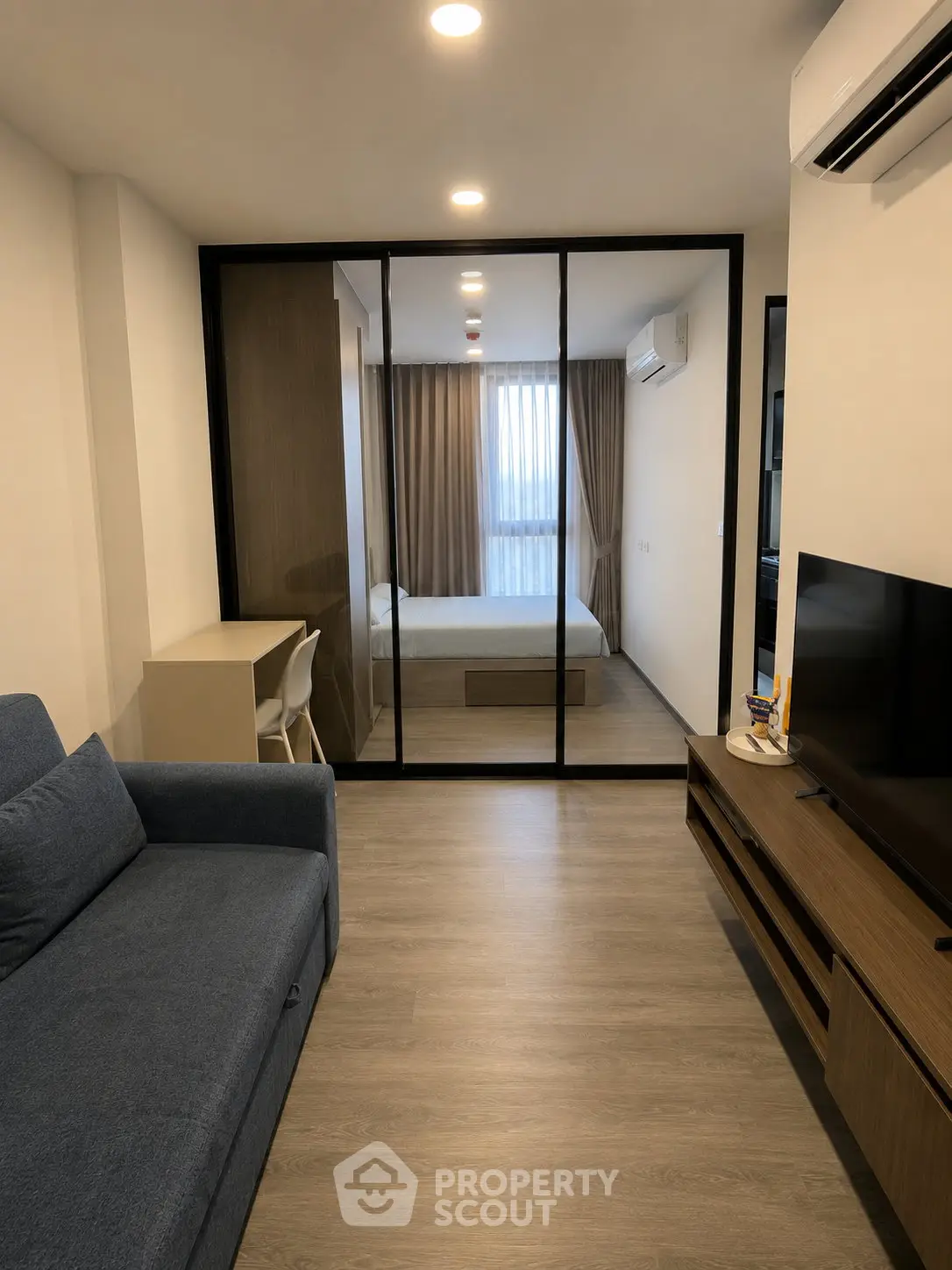 Modern studio apartment with glass partition, cozy living area, and stylish bedroom.