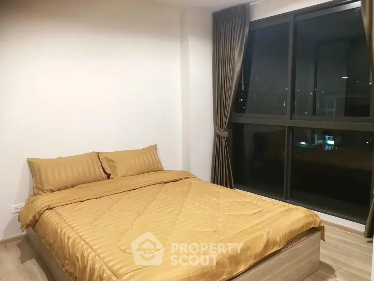 Cozy bedroom with large window offering stunning night views, featuring a comfortable bed and elegant curtains.