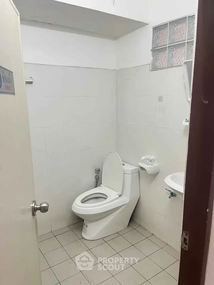 Compact bathroom with white tiles and modern toilet in a minimalist design.