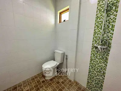Modern bathroom with tiled walls and shower area in a real estate property.