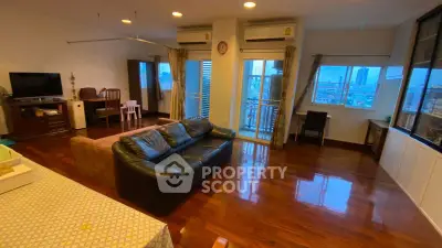 Spacious living room with polished wooden floors and city view balcony in modern apartment.