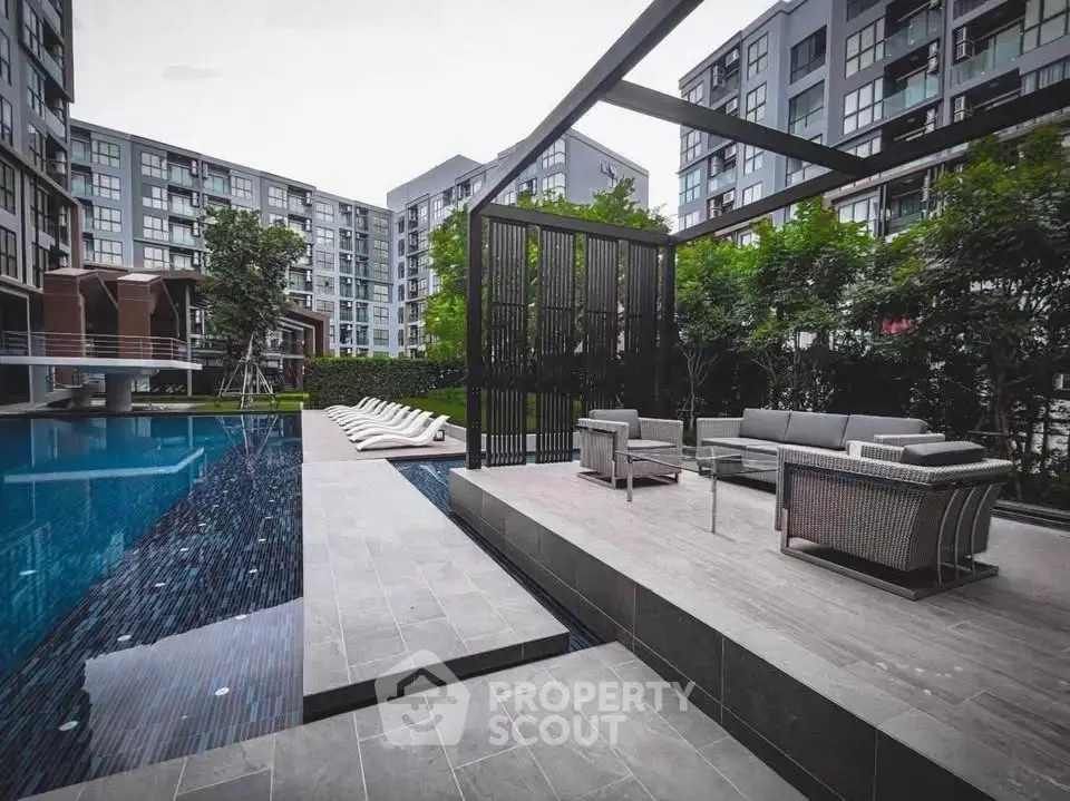 Luxurious modern apartment complex with stylish poolside lounge area and contemporary architecture.