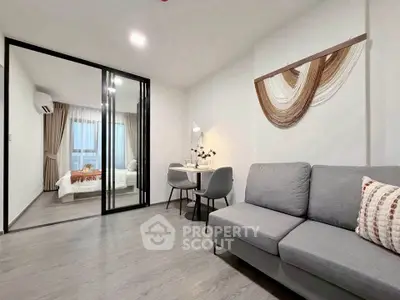 Modern living room with stylish decor and view into cozy bedroom through glass doors.