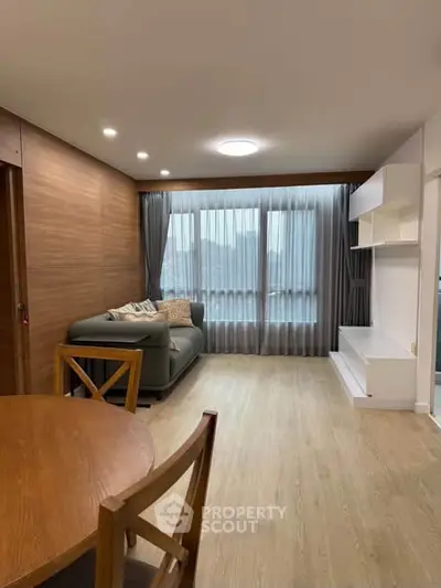Modern living room with wooden flooring, cozy sofa, and elegant curtains in a stylish apartment.
