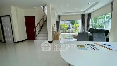Spacious modern living room with large windows and elegant staircase in a bright home.