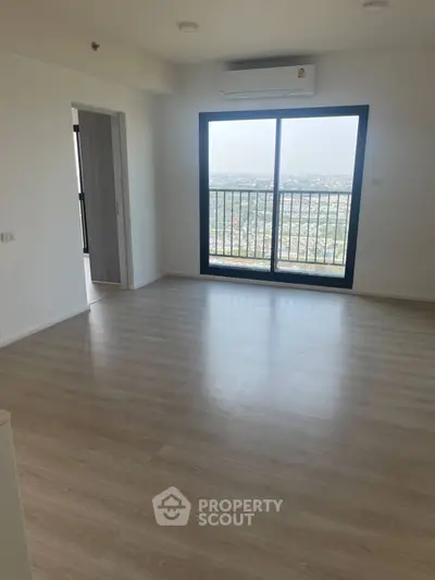Spacious living room with large window offering stunning city views in modern apartment.