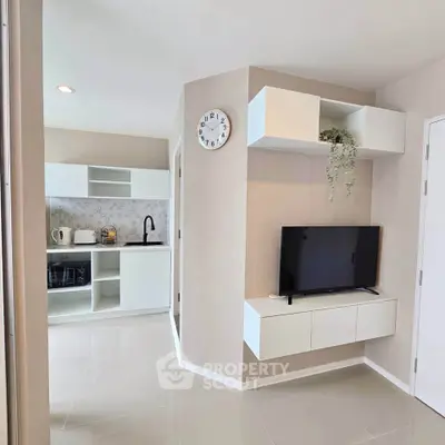 Modern apartment interior with sleek kitchen and cozy living area featuring wall-mounted TV.
