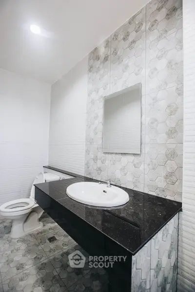 Modern bathroom with sleek black countertop and stylish hexagonal tiles.