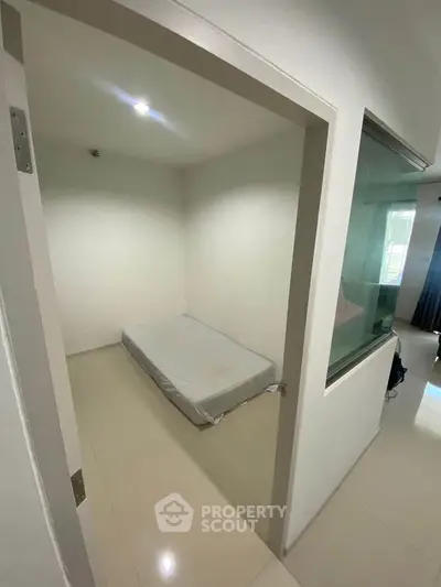 Minimalist small bedroom with single mattress and white walls, ideal for compact living spaces.