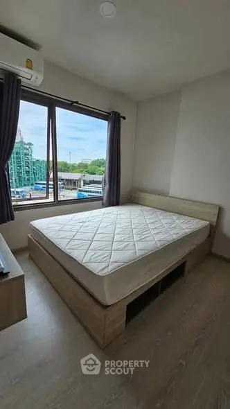 Cozy bedroom with large window offering city views, featuring a comfortable bed and modern air conditioning unit.