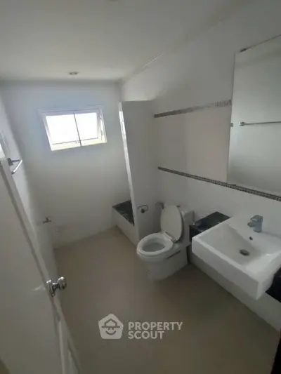 Compact bathroom with modern fixtures and natural light from window.