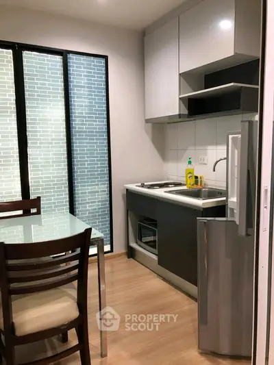 Modern kitchen with sleek cabinetry and dining area, featuring a glass table and wooden chairs.