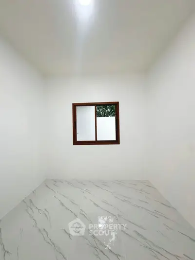 Minimalist room with marble flooring and a window, perfect for a cozy home office or study space.