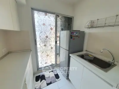 Modern kitchen with sleek design, featuring a fridge and stylish frosted glass door.