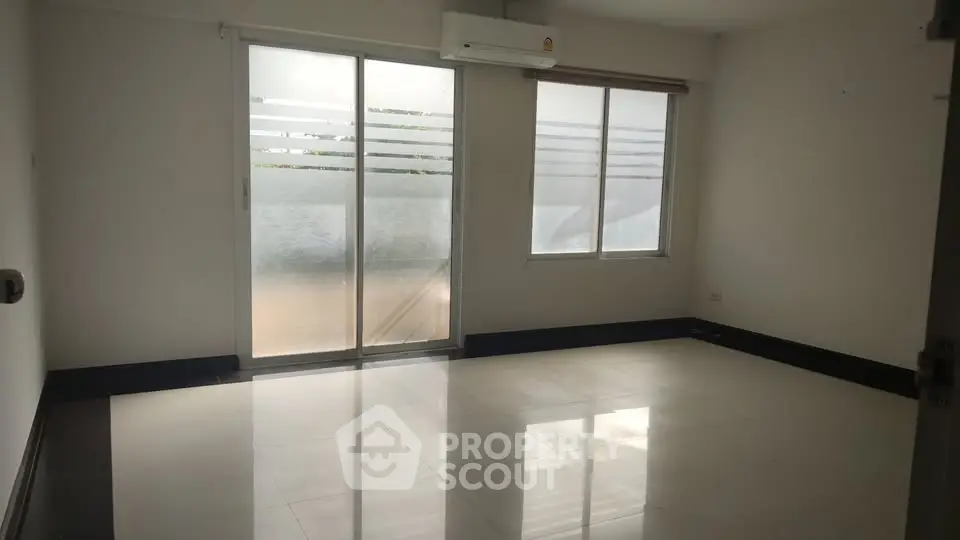 Spacious unfurnished room with large windows and air conditioning unit.