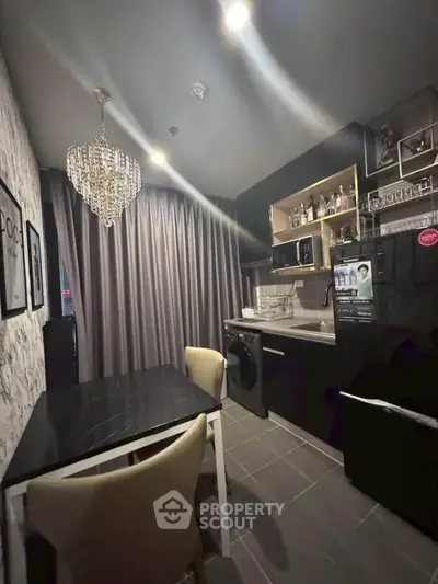 Modern kitchen with elegant chandelier and sleek black appliances in a stylish apartment.