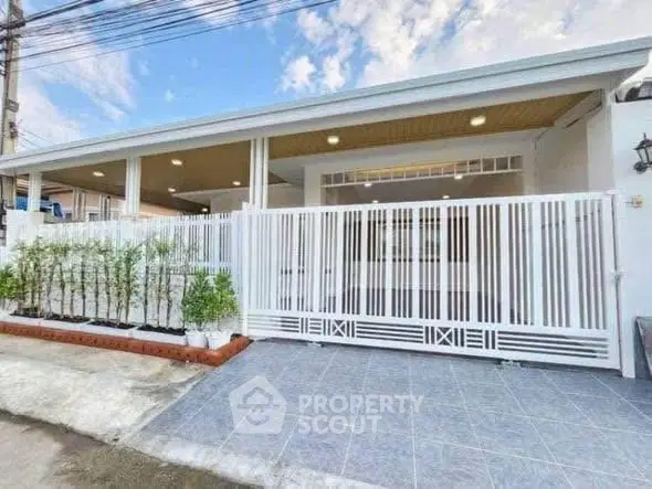 Modern single-story home with spacious front patio and sleek white fence.