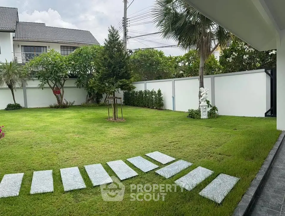 Spacious garden with lush greenery and modern pathway in a serene residential area.