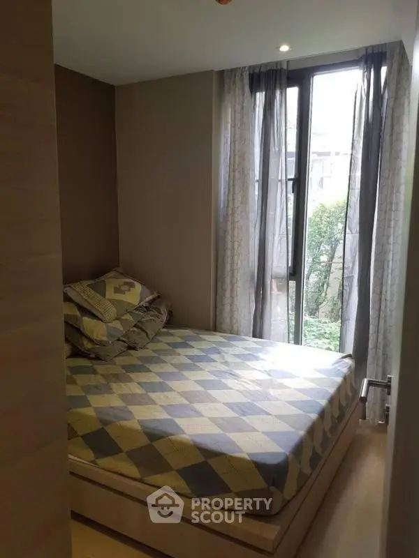 Cozy bedroom with large window and stylish bedding in modern apartment.