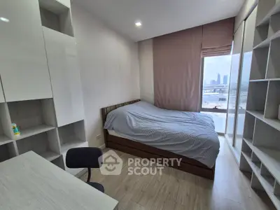 Modern bedroom with city view, featuring sleek storage and cozy bed setup.