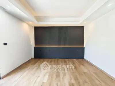 Spacious modern living room with elegant wood flooring and stylish accent wall.