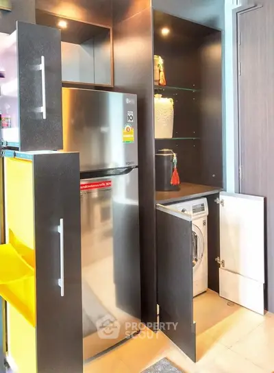 Modern kitchen with sleek cabinets, stainless steel fridge, and built-in washing machine.