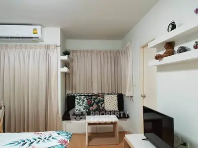 Cozy living room with modern decor and air conditioning, featuring a comfortable seating area and stylish shelving.