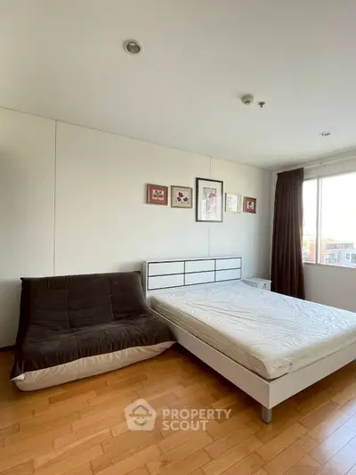 Spacious bedroom with modern decor and large window offering natural light.
