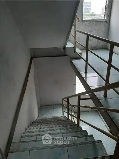 Spacious stairwell with natural light and modern railing in a residential building.