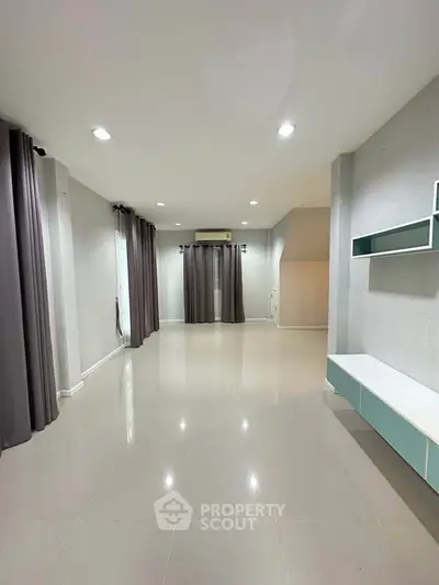 Spacious modern living room with sleek tile flooring and minimalist decor.