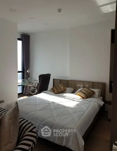 Cozy bedroom with modern decor and natural light, featuring a comfortable bed and stylish desk.