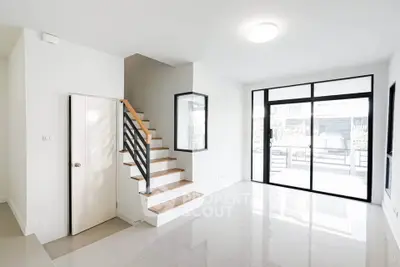 Modern minimalist living room with staircase and large windows