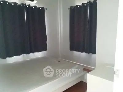 Cozy bedroom with dark curtains and minimalist decor, perfect for restful nights.