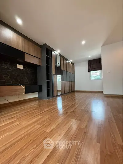 Spacious modern bedroom with wooden flooring and built-in wardrobe