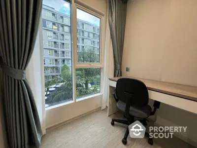 Modern study room with a view of apartment complex and lush greenery.