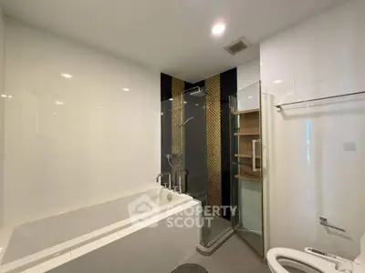 Modern bathroom with bathtub and glass shower enclosure in a sleek apartment.