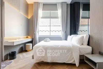 Modern bedroom with elegant decor and natural light, featuring a cozy bed and stylish furnishings.