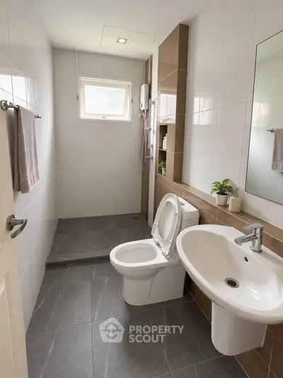 Modern bathroom with sleek fixtures and natural light, featuring a shower and stylish tiling.