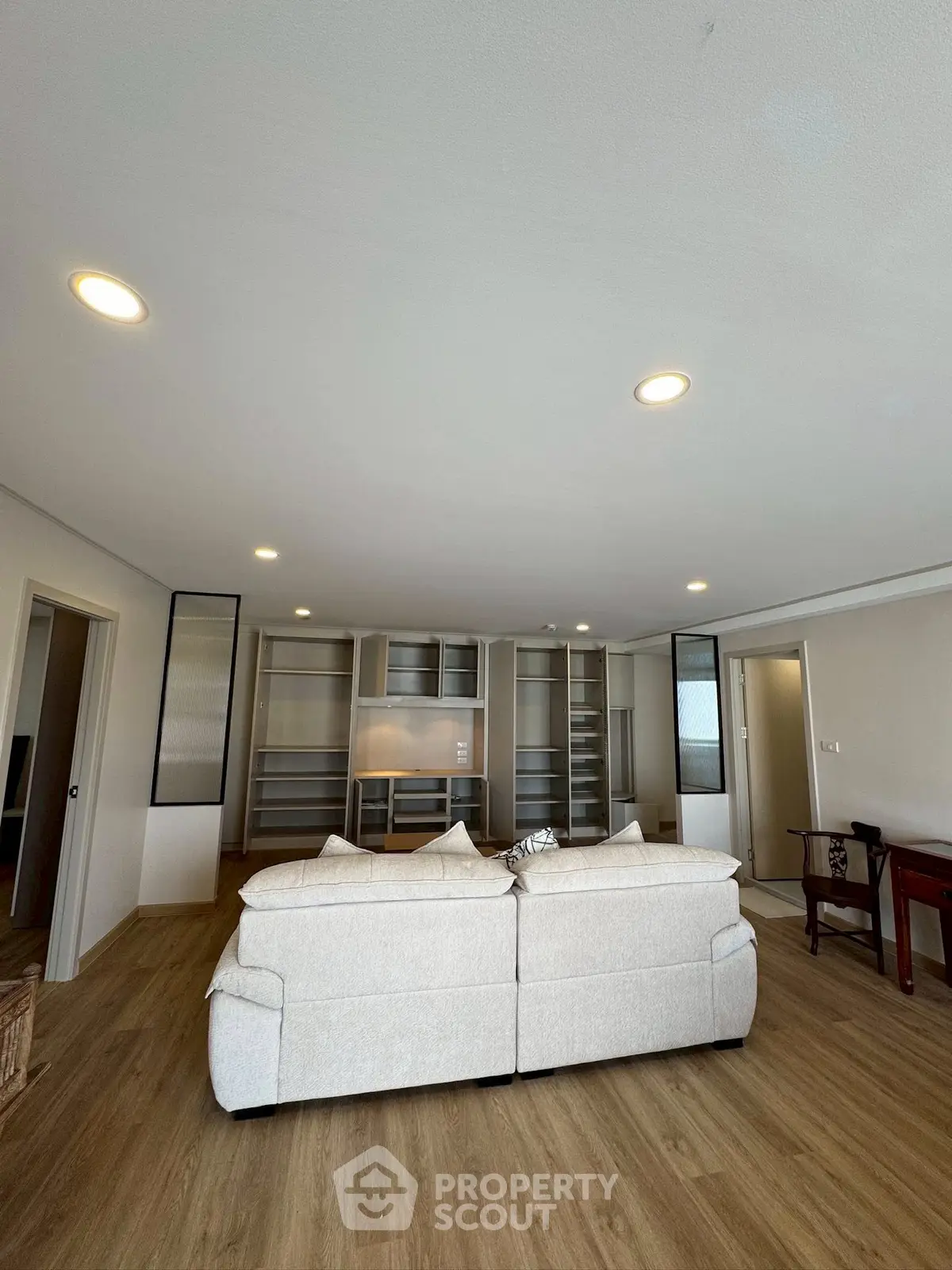 Spacious living room with modern built-in shelves and cozy seating area, perfect for relaxation and entertainment.