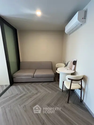 Modern living room with sleek sofa and stylish chairs, featuring elegant flooring and air conditioning.