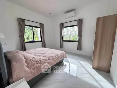 Spacious bedroom with large windows and modern air conditioning unit, offering serene views and ample natural light.