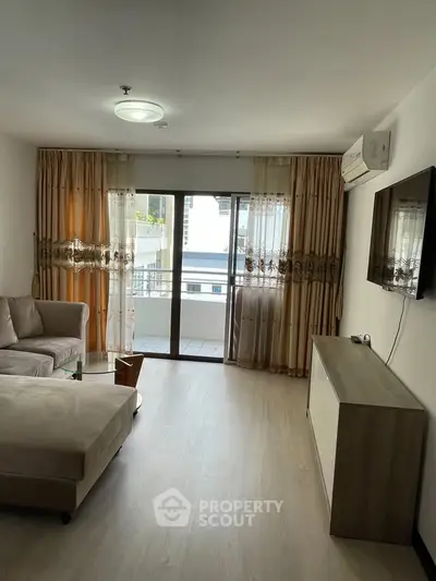 Spacious living room with modern decor and large balcony access, perfect for relaxation and entertainment.