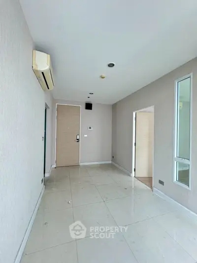 Spacious modern apartment interior with sleek tile flooring and air conditioning, ideal for comfortable living.