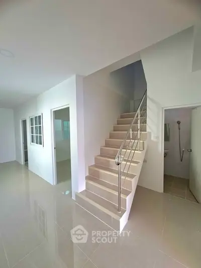 Modern interior with sleek staircase and tiled flooring in a bright, spacious home.
